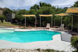 a swimming pool with two chairs and umbrellas at Vado Biguá in Valle Hermoso