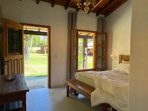 a bedroom with a bed and a door to a yard at Chalés Pequena Floresta in Cunha