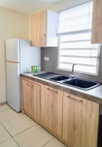 a kitchen with a sink and a white refrigerator at T3 Serenity aux couleurs du soleil à Ducos in Ducos +2 photos