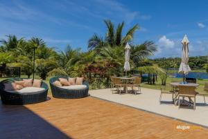 a patio with two chairs and tables and umbrellas at Apartamento Cobertura em Guarajuba Perto do Mar in Camaçari