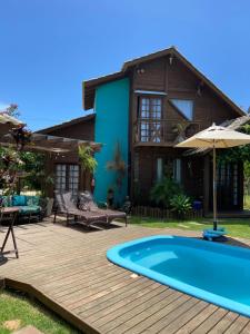 a house with a wooden deck and a swimming pool at Villa Rosa e Mar - Praia do Rosa in Imbituba