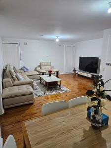 a living room with couches and a flat screen tv at Campbelltown Family Retreat 3-Bedroom Home in Campbelltown