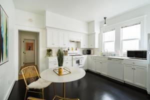 a kitchen with white cabinets and a table and chairs at The Art Deco Lounge - 95 WalkScore - Live Music in Portland