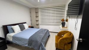 a bedroom with a bed and a chair and a window at Apartamento de lujo in Ibarra