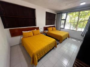 a hotel room with two beds with yellow sheets at Hotel "Casa Las Lolas" in Xpujil +50 photos