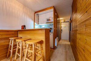 a kitchen with a bar with stools in it at Ski in and out heart of Val Thorens - 1BR Sleeps 4 people in Val Thorens