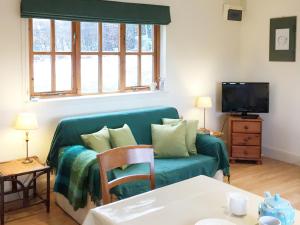 a living room with a couch and a tv at The Wee House in Muthill +3 photos