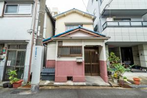 a small red and white house in a city at A comfortable house with easy access to Osaka city in Osaka