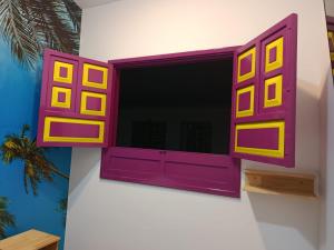 a window on a wall with a purple and yellow at Jardinhabs - JARDÍN in Filandia