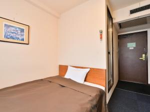 a small bedroom with a bed and a door at Suzuka Royal Hotel in Suzuka