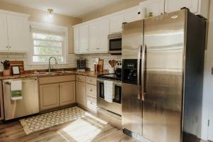 a kitchen with a stainless steel refrigerator and white cabinets at The Atlas - Family-Focused Stay for Every Journey in Fargo