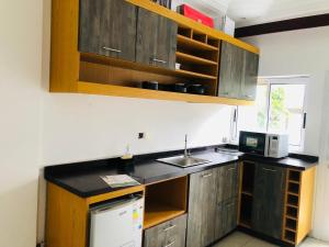 a kitchen with wooden cabinets and a sink and a microwave at residence hoteliere samba in Douala