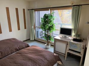 a bedroom with a bed and a desk with a computer at フューデイズコンドミニアム定山渓201号室 in Jozankei