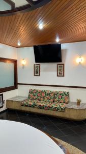 a couch in a room with a flat screen tv at Motel Casa Branca in Blumenau