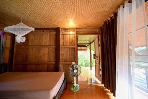 a bedroom with a bed with a fan and a window at KowitFarmstay in Ban Mae Pan Noi