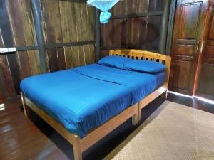 a wooden bed with blue sheets in a room at KowitFarmstay in Ban Mae Pan Noi