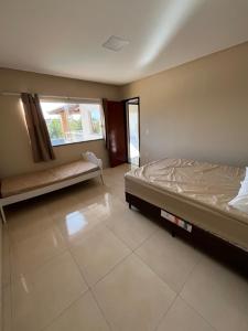 un dormitorio vacío con una cama y una ventana en Vivenda da Alegria, en Vera Cruz de Itaparica