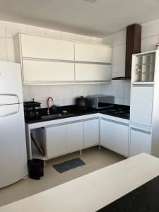 Una cocina con gabinetes blancos y un refrigerador blanco. en Vivenda da Alegria, en Vera Cruz de Itaparica