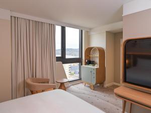 una habitación de hotel con una cama y una ventana grande en voco Gosford by IHG, en Gosford