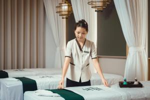 a woman standing between two beds in a hotel room at Cat Ba Wistaria Hotel- Jacuzzi Rooftop & Fitness in Cat Ba +56 photos