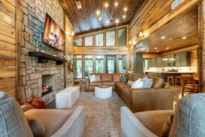 a living room with couches and a stone fireplace at Nectars Ridge - Heated Pool, Hot Tub, Ping Pong, Arcade in Broken Bow