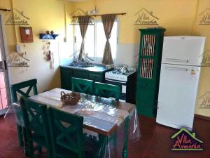 Una cocina con una mesa y un refrigerador blanco. en Villa Armonia, en La Picada