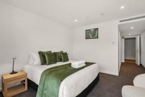 - une chambre blanche avec un lit et des oreillers verts dans l'établissement Lakefront Luxury 3 Bedroom Apartment, à Wanaka