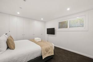 une chambre blanche avec un lit et une télévision dans l'établissement Lakefront Luxury 2 Bedroom Apartment, à Wanaka