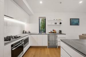 une cuisine blanche avec une cuisinière et un évier dans l'établissement Lakefront Luxury 2 Bedroom Apartment, à Wanaka 13 autres photos
