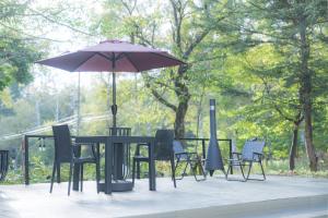 a table and chairs with an umbrella in a park at Komakusa Hotel in Matsumoto