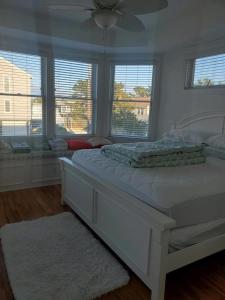 a white bedroom with a large bed with windows at Oceanside Single Family Brant Beach Beach Badges Rooftop Deck Wifi Private Yard Washer & Dryer in Beach Haven Crest