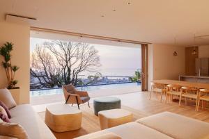 Asnova Resort FLORES ATAMI في أتامي: غرفة معيشة مع طاولة ونافذة كبيرة