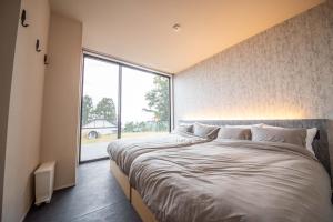 a bedroom with two beds and a large window at Doggo伊豆　愛犬と過ごす最高の時間の為に造られた貸切宿。温泉、プライベートドッグランで最高の一時を。 in Ito