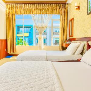 two beds in a hotel room with a window at Tâm Tín Hotel Hồ Chí Minh in Ho Chi Minh City
