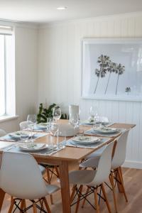 - une table à manger avec des verres à vin et des chaises blanches dans l'établissement Magpie Sands - Ocean Views & Seaside Luxury - Steps to beach, à Aldinga Beach