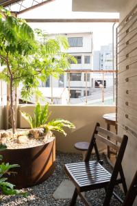 Un balcón con una silla y una mesa y árboles. en sishi hostel, en Tainan