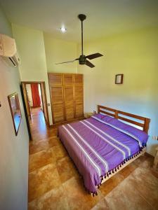 a bedroom with a purple bed with a ceiling fan at Penthouse en Huatulco con alberca, balcón, 5 min playa in Santa Cruz Huatulco