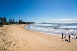 a group of people walking on a beach at Ocean Vista Retreat - Walk to Mooloolaba & Alex in Mooloolaba