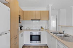 a kitchen with white cabinets and a sink at Ocean Vista Retreat - Walk to Mooloolaba & Alex in Mooloolaba +8 photos