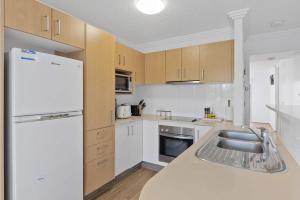 Ocean Vista Retreat - Private Rooftop Spa by the Sea في مولولابا: مطبخ مع مغسلة وثلاجة بيضاء