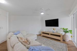 Ocean Vista Retreat - Private Rooftop Spa by the Sea في مولولابا: غرفة معيشة مع أريكة وتلفزيون بشاشة مسطحة