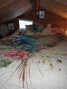 ein Bett mit einer weißen Bettdecke mit Blumen darauf in der Unterkunft Tree House 4 Two in Rotorua