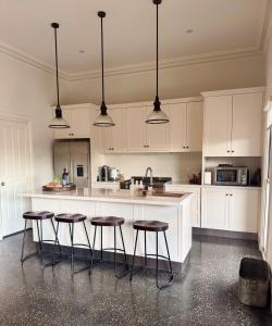 a kitchen with white cabinets and bar stools at Barossa Bed & Breakfast in Tanunda +13 photos