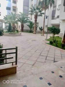 a bench in a courtyard with palm trees and a building at Perfect Studio Apartment La Cañada in Fès