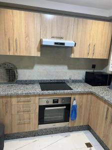 a kitchen with wooden cabinets and a stove top oven at Perfect Studio Apartment La Cañada in Fès +5 photos