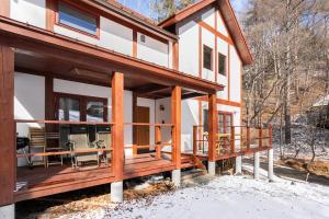 een huis met een veranda rondom in de sneeuw bij Riveret Karuizawa in Karuizawa