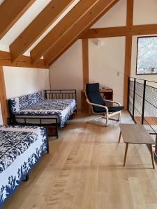 een kamer met 2 bedden, een stoel en een tafel bij Riveret Karuizawa in Karuizawa