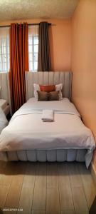 a bedroom with a large white bed with orange curtains at Embu Pacific Homes Two Bedroom in Embu