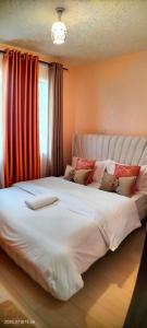 a large white bed in a room with a window at Embu Pacific Homes Two Bedroom in Embu