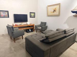 a living room with a couch and two chairs and a television at Sweet Laguna Luxury House in Iguaba Grande